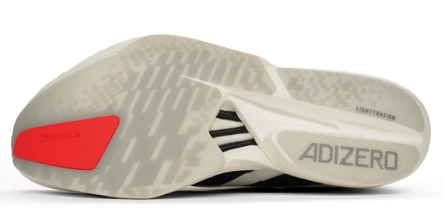 Bottom view of Adidas Adizero Adios Pro 4 showing LightTraxion outsole, red Continental rubber heel patch, and black carbon rods