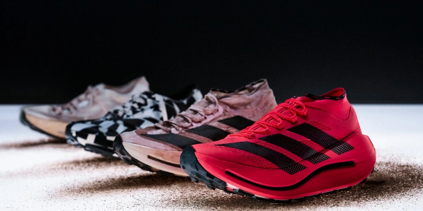 Three Adidas Terrex Agravic Evo trail running shoes in red, pink, and grey camo displayed on a studio surface