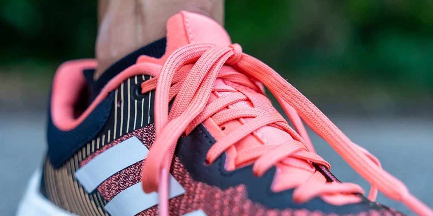 Close-up of Adidas Terrex Soulstride Flow running shoe in coral pink and navy with three-stripe branding and flat laces