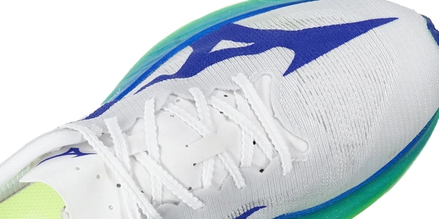 Close-up of Mizuno Hyperwarp Collective running shoe upper with white knit fabric, blue wave logo, white laces and teal midsole