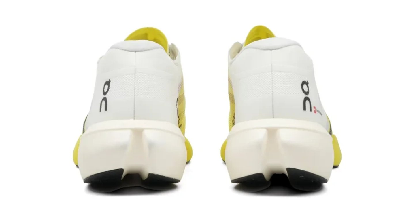 Rear view of a pair of On Cloudboom Strike 2.5 running shoes in white and yellow, showing heel counter and midsole.