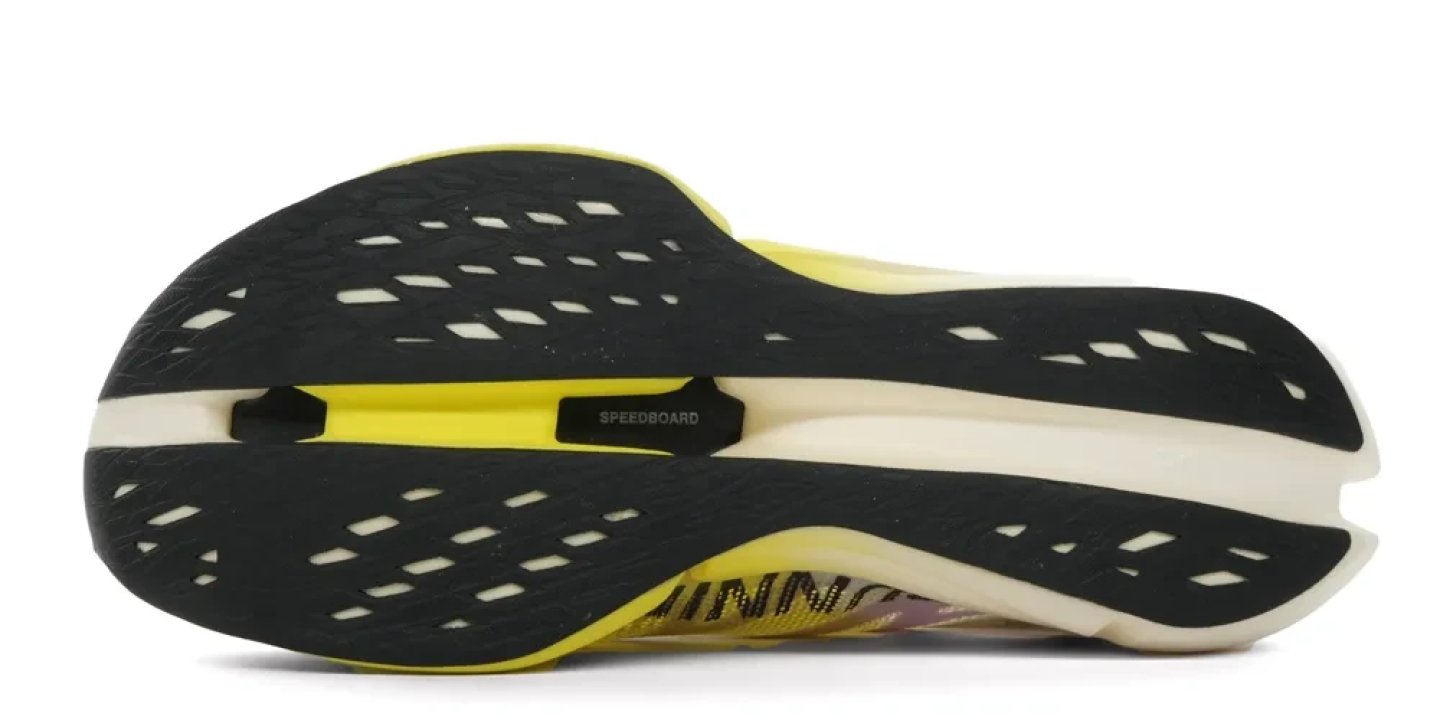 Bottom view of the On Cloudboom Strike 2 running shoe showing black perforated rubber outsole with Speedboard carbon plate and yellow midsole