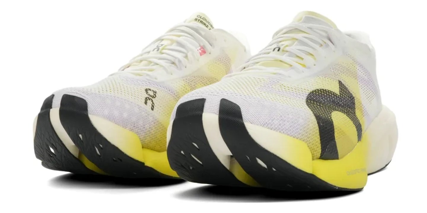 On Cloudboom Strike 2 running shoes in white and yellow, rear three-quarter view showing midsole and heel detail