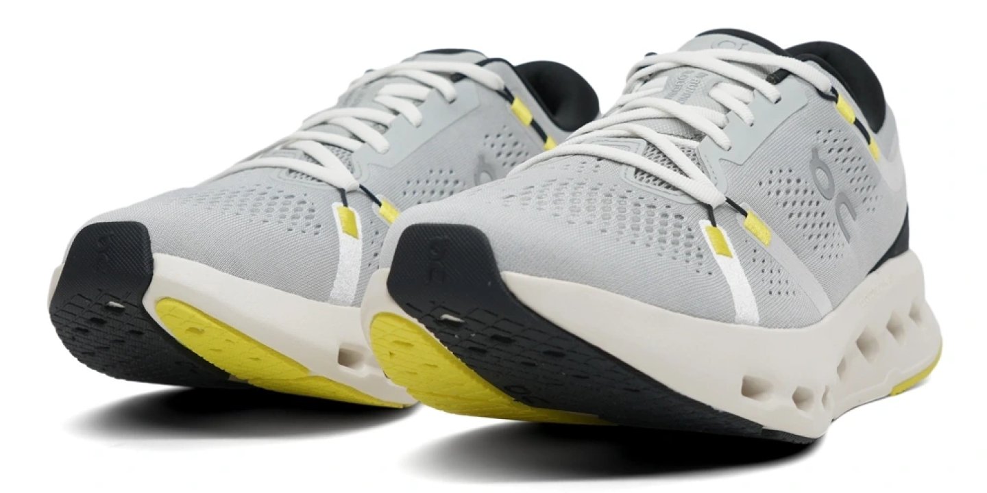 On Cloudsurfer 2 running shoe in glacier grey and yellow, shown from a front three-quarter angle highlighting CloudTec sole