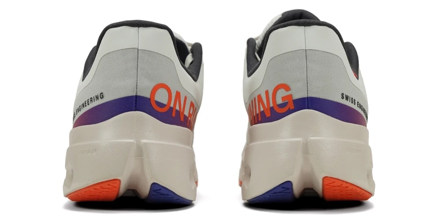 Heel view of the On Cloudsurfer Next running shoe in white with orange and purple CloudTec outsole pods and Swiss Engineering branding