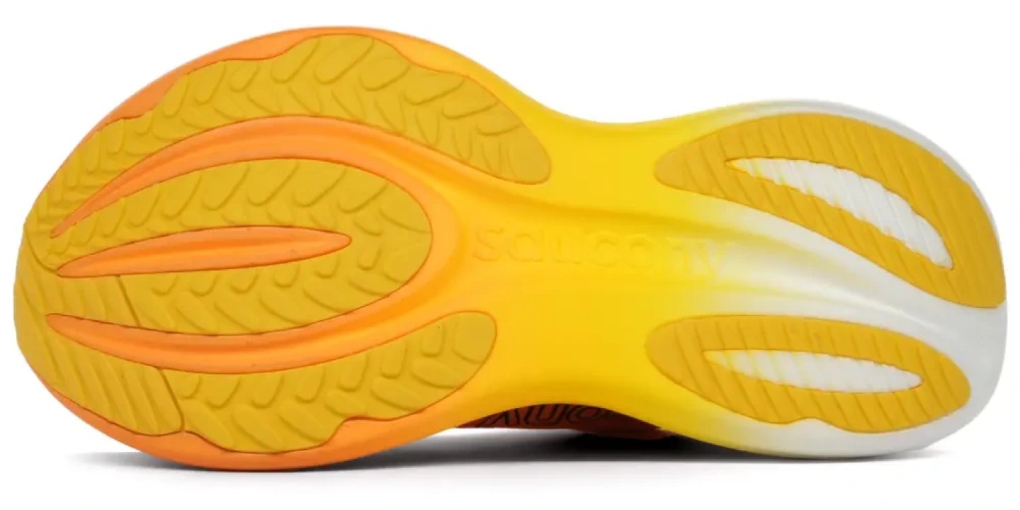 Bottom view of the Saucony Triumph 24 running shoe outsole in yellow and orange, showing traction pods and flex grooves.