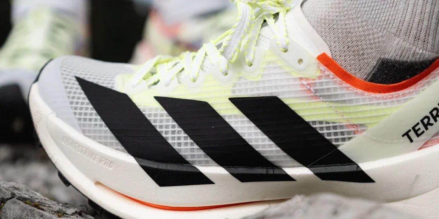 Adidas Terrex Agravic Pro trail running shoe in white and lime green with black three stripes and orange outsole accent.