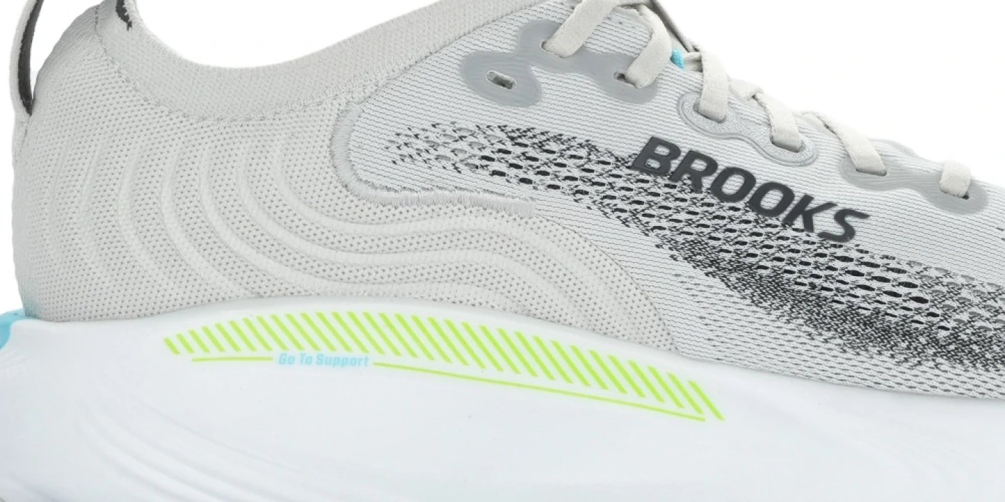 Close-up of the Brooks Adrenaline GTS 25 showing the knit upper, mesh ventilation zones and Go To Support midsole in grey and lime.