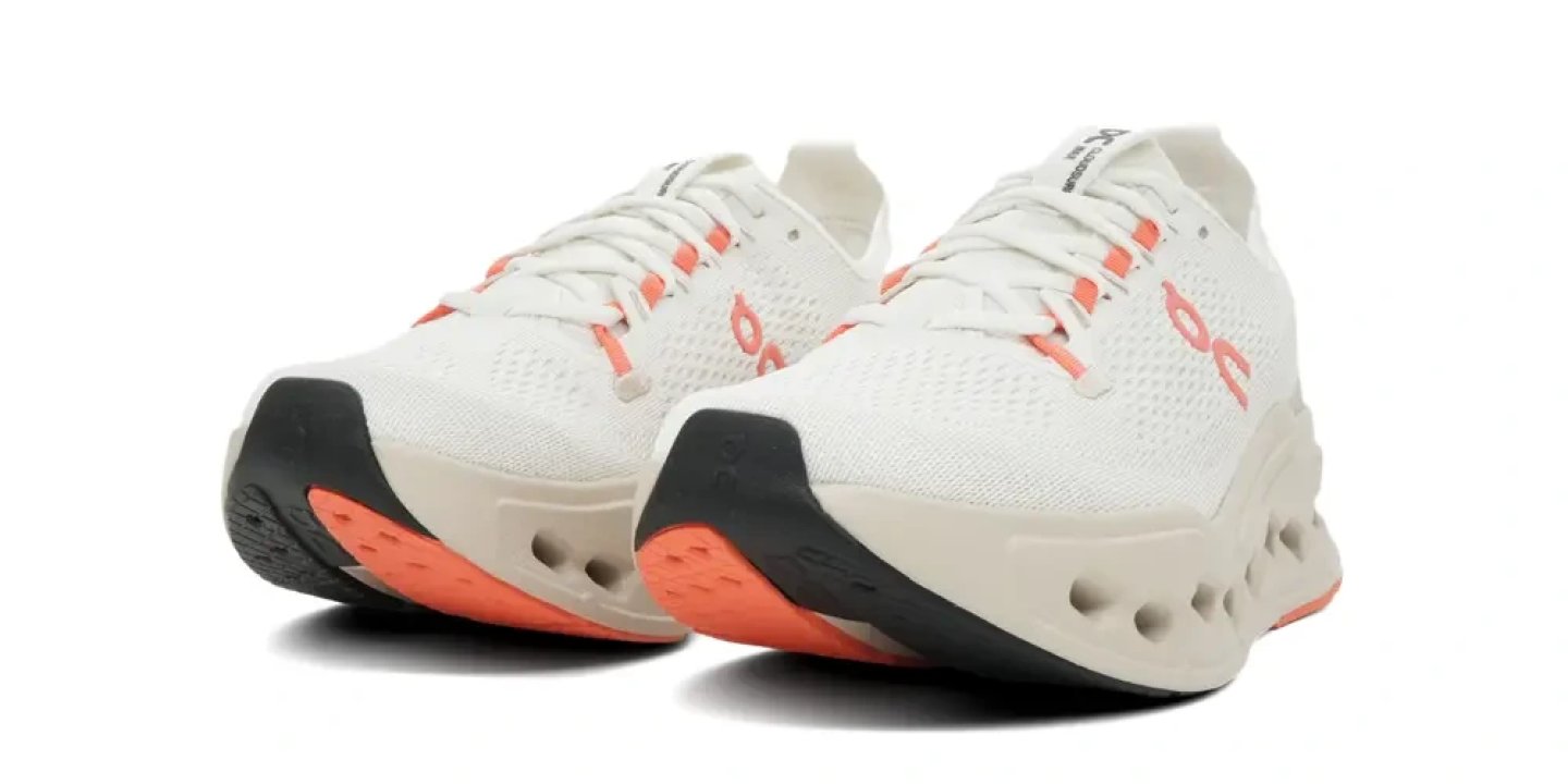 On Cloudsurfer Max 4 running shoes in white and flame orange, shown as a pair from a front-side angle