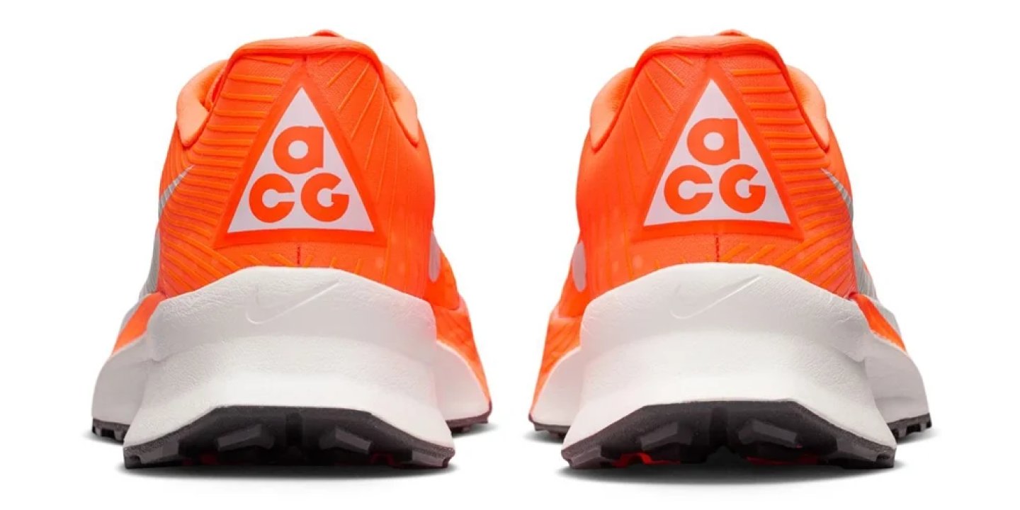 Rear view of Nike ACG trail running shoes in bright orange with white ACG triangle logo on the heel counter.