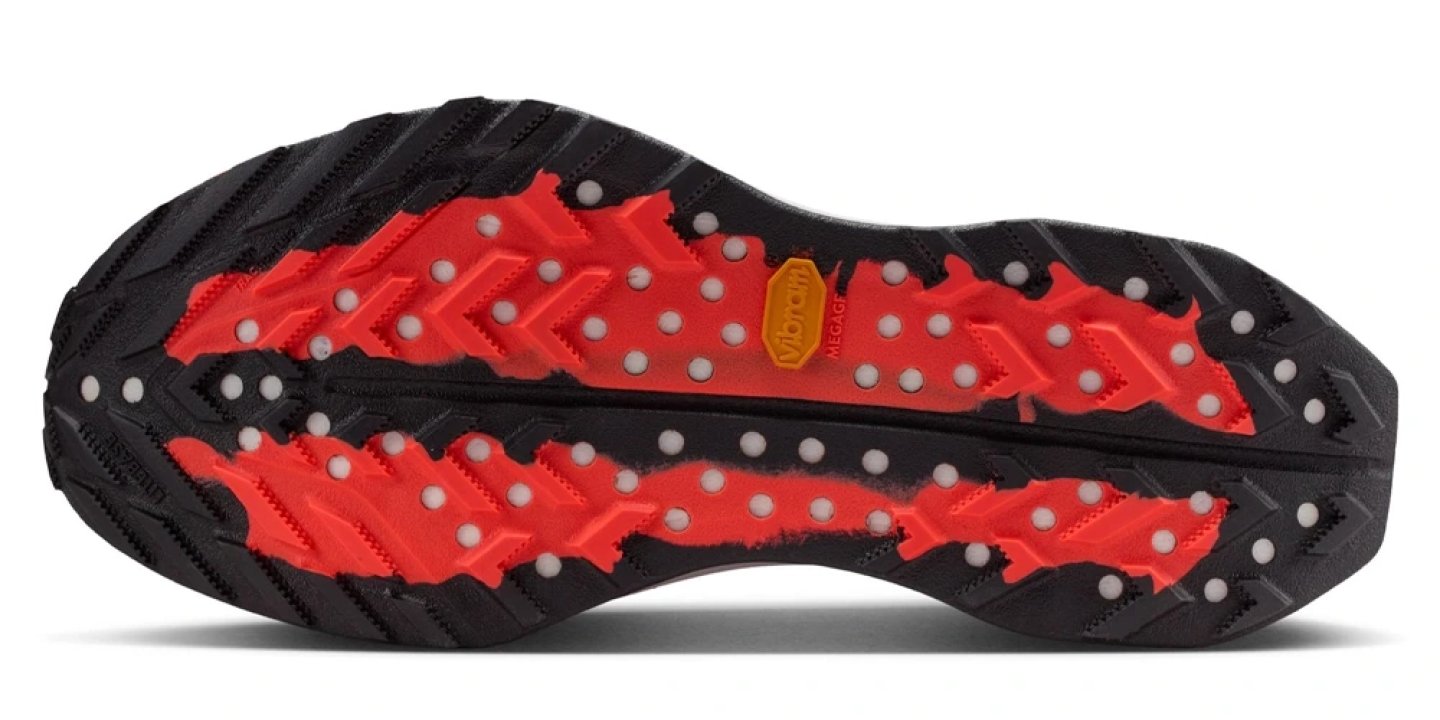 Bottom view of Nike ACG Ultrafly Trail running shoe outsole showing red Vibram Megagrip lugs and black rubber on white background.