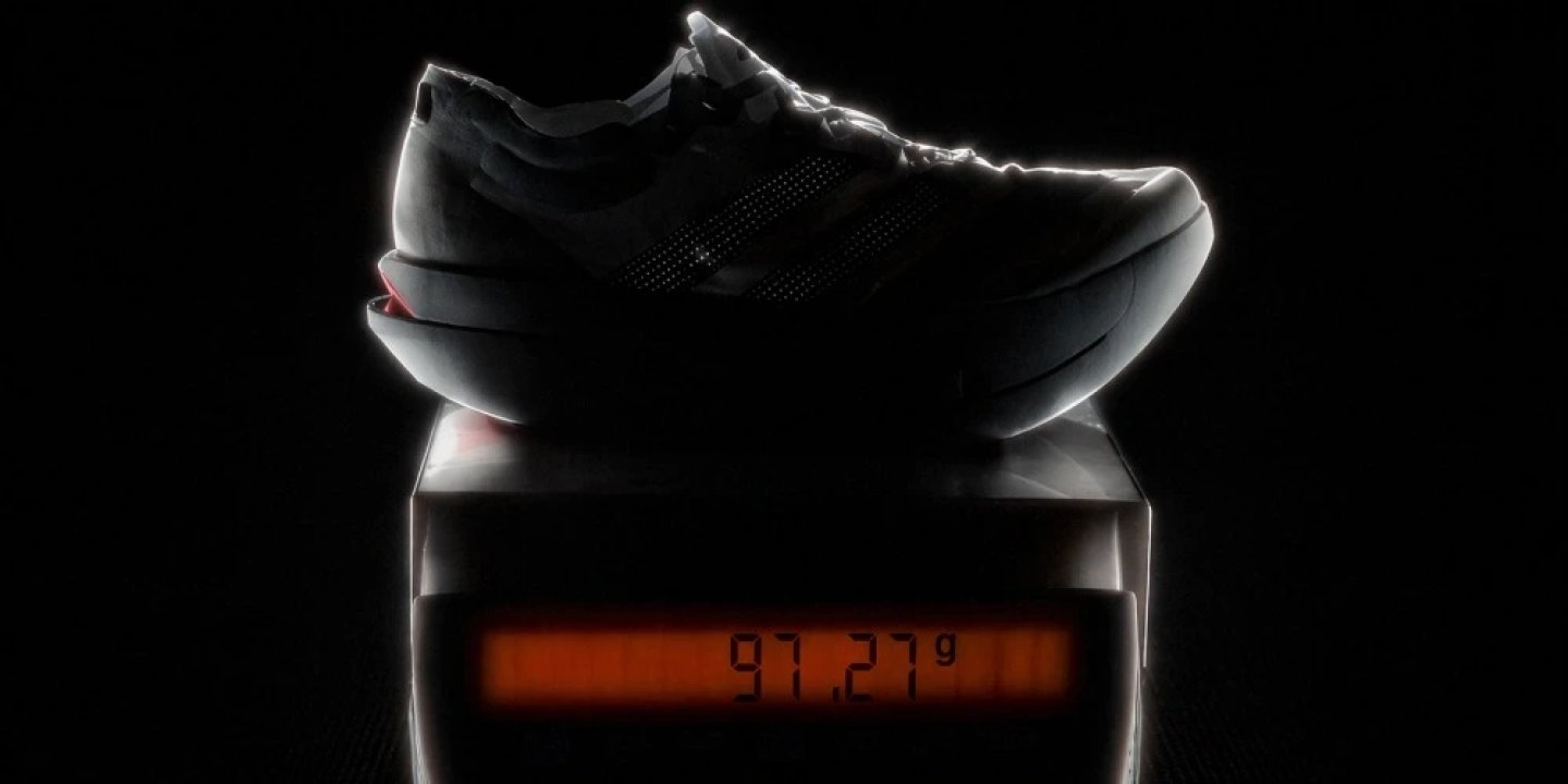 Adidas Adizero Adios Pro Evo 3 racing shoe resting on a digital scale displaying 97.27 grams against a dark background.