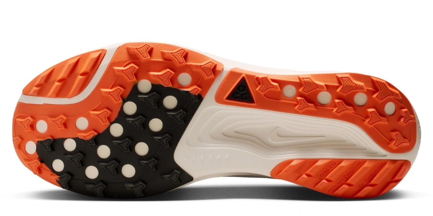 Bottom view of Nike ACG Pegasus Trail Zoo running shoe outsole with orange and black multi-directional lugs and white midsole