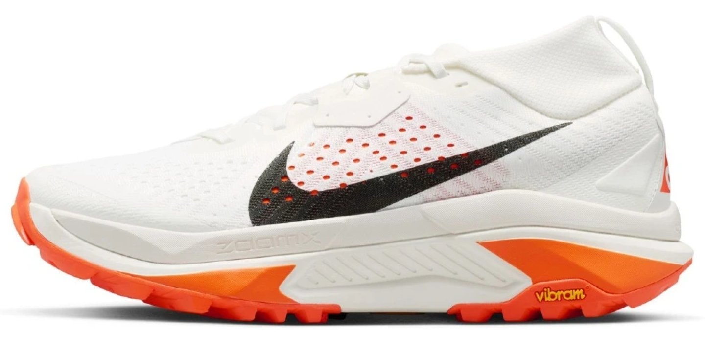 Nike ACG Zegama trail running shoe in white and orange with ZoomX midsole and Vibram outsole, lateral view