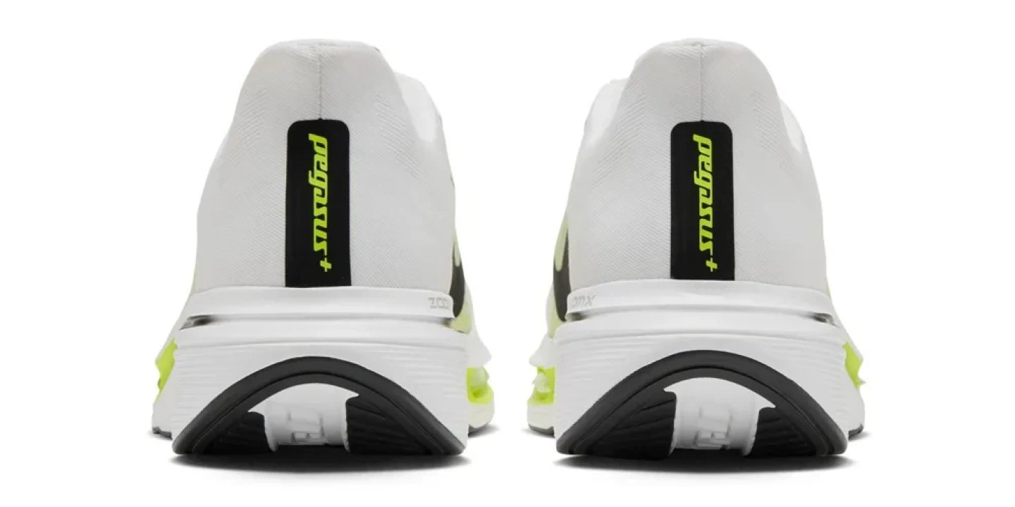 Rear view of two Nike Pegasus Plus 2 running shoes in white and volt green, showing heel tab branding and ZoomX midsole.