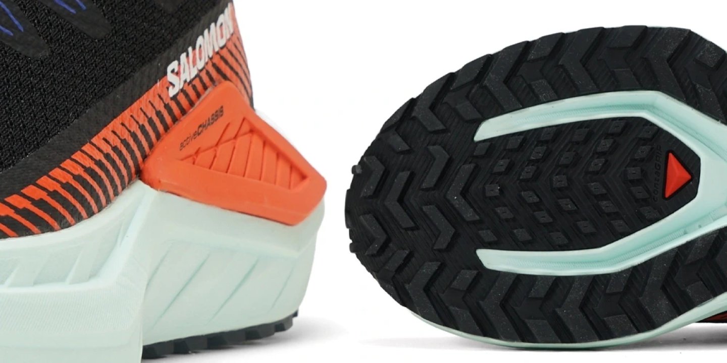 Close-up of Salomon DRX DEFY TRVL trail running shoe heel and outsole showing black lug tread pattern, mint midsole, and orange EnergyChassis