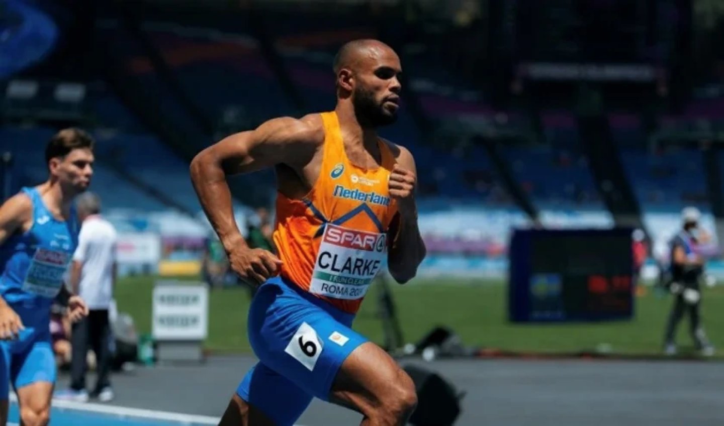 Sprinter Clarke in Netherlands orange ASICS singlet and blue shorts racing in lane 6 at Roma European Athletics Championships.