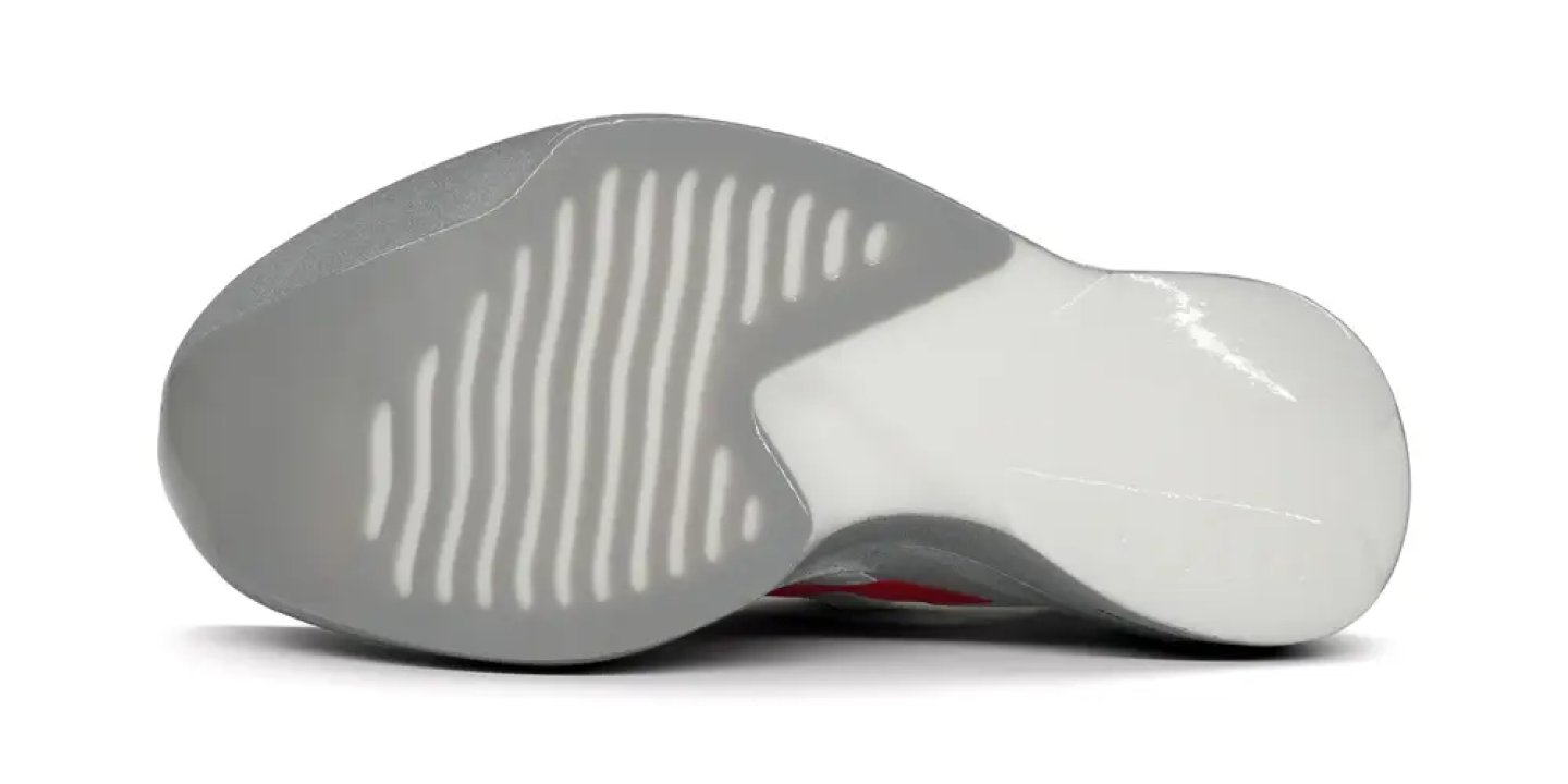 Bottom view of Adidas Adizero running shoe outsole showing grey linear flex grooves and white forefoot pod.