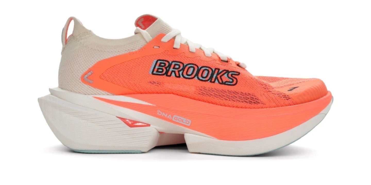 Brooks running shoe with bright orange mesh upper, white DNA Gold midsole and carbon plate technology, lateral view