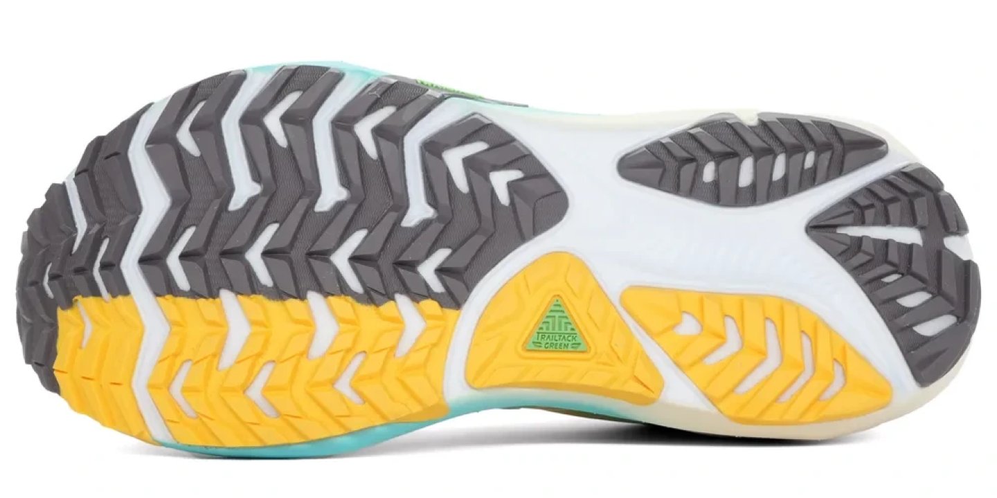 Bottom view of Brooks Ghost Trail men's running shoe outsole showing grey and yellow TrailTack Green rubber lugs and chevron traction pattern.