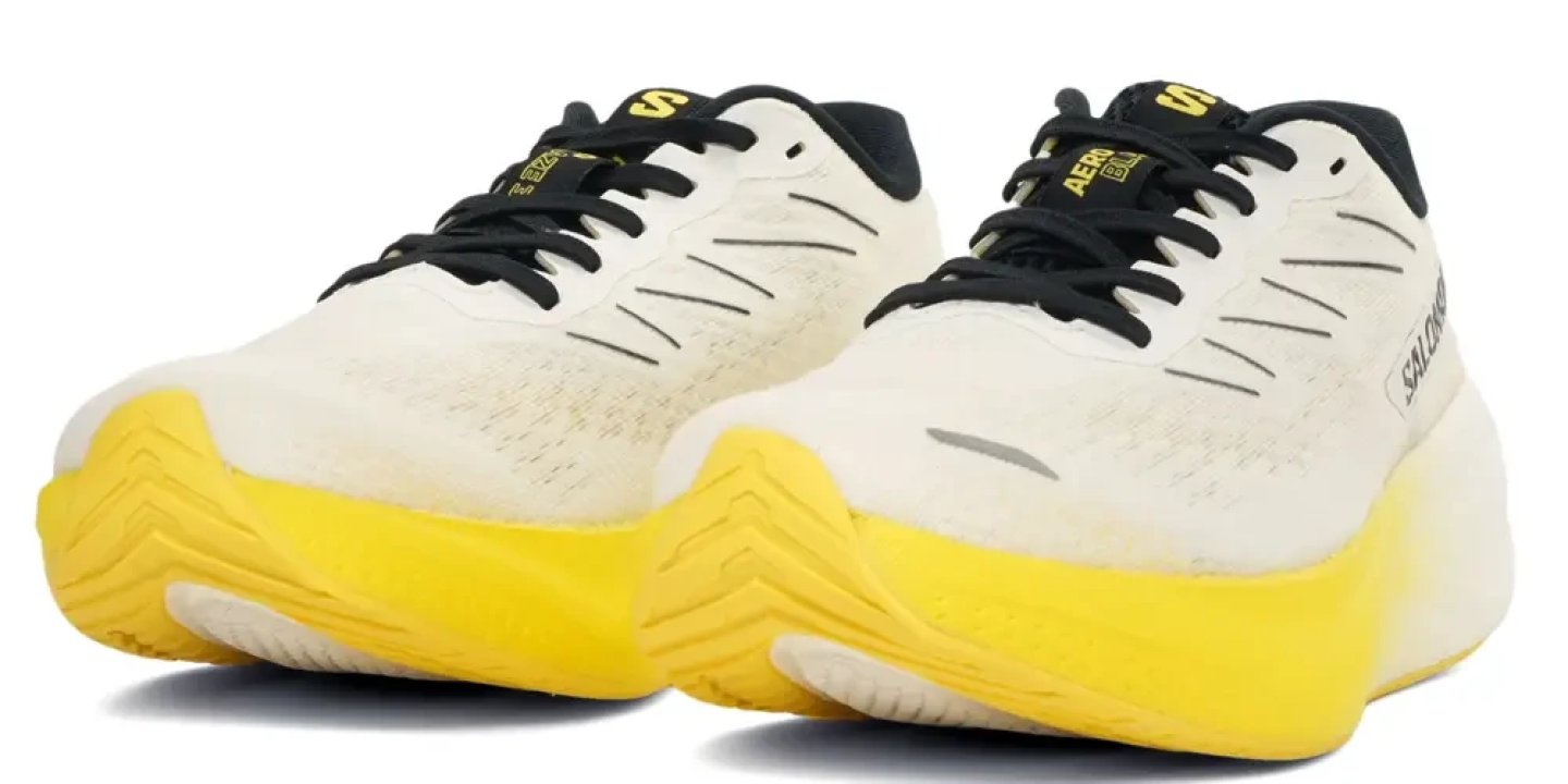 Salomon Aero Glide running shoes in white and black with bright yellow midsole, pair shown from front angle