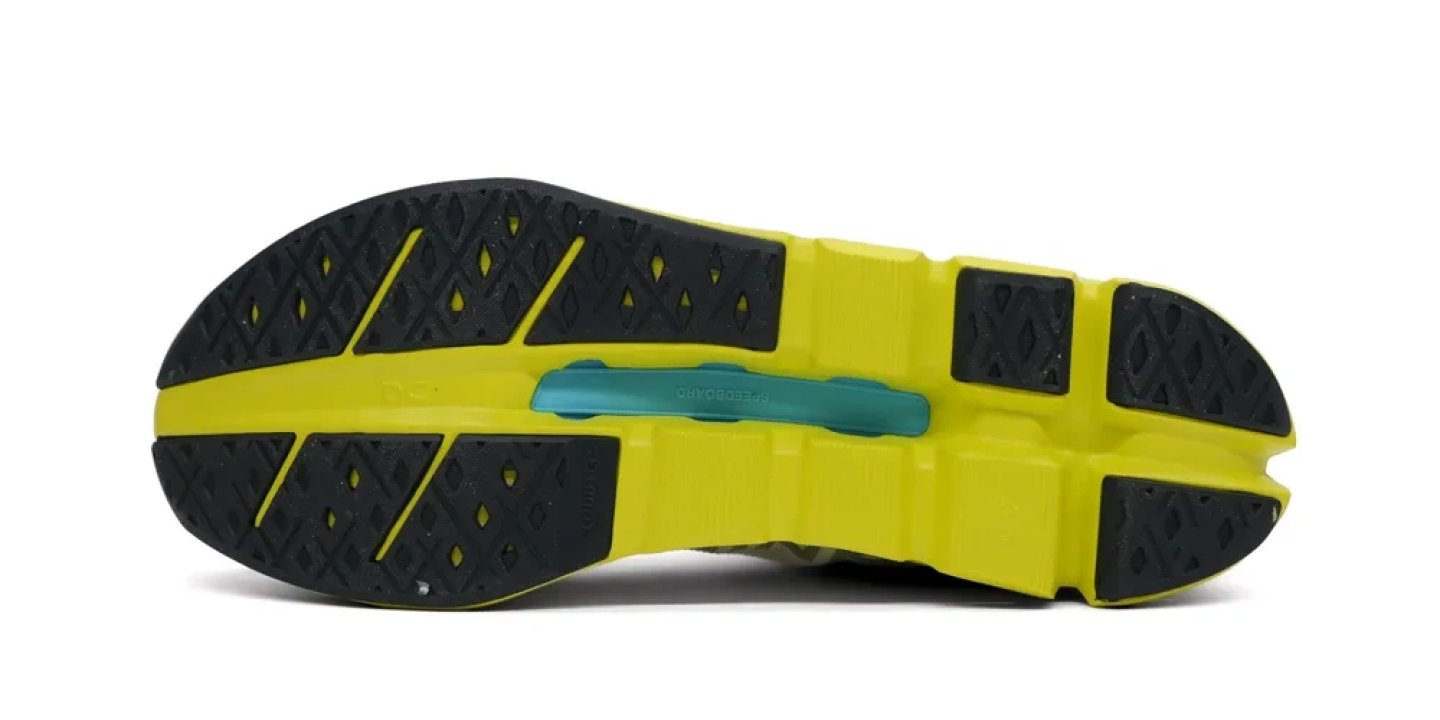 Bottom view of the On Cloudflow 5 outsole showing black rubber grip lugs, yellow midsole channels and a teal CloudTec element