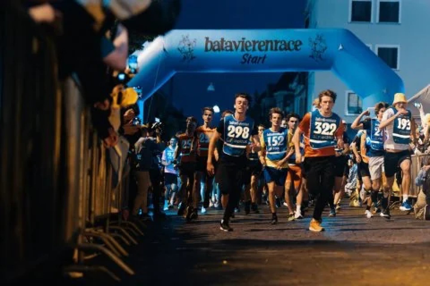 Runners crossing the Batavierenrace start line at night, led by Menno Munster wearing bib 298.