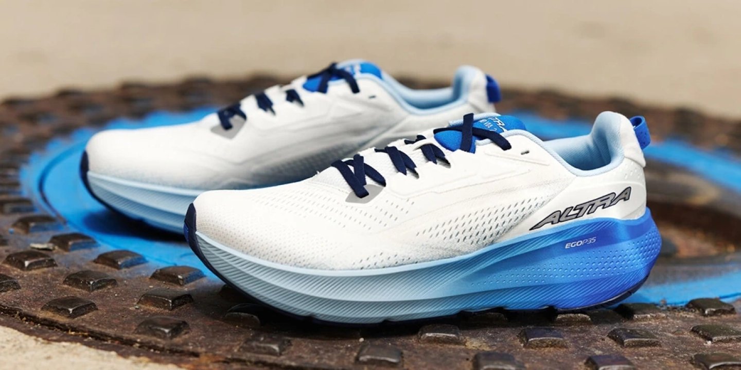 Altra EGO P35 running shoes in white and blue colourway displayed on a metal surface, showing mesh upper and midsole detail