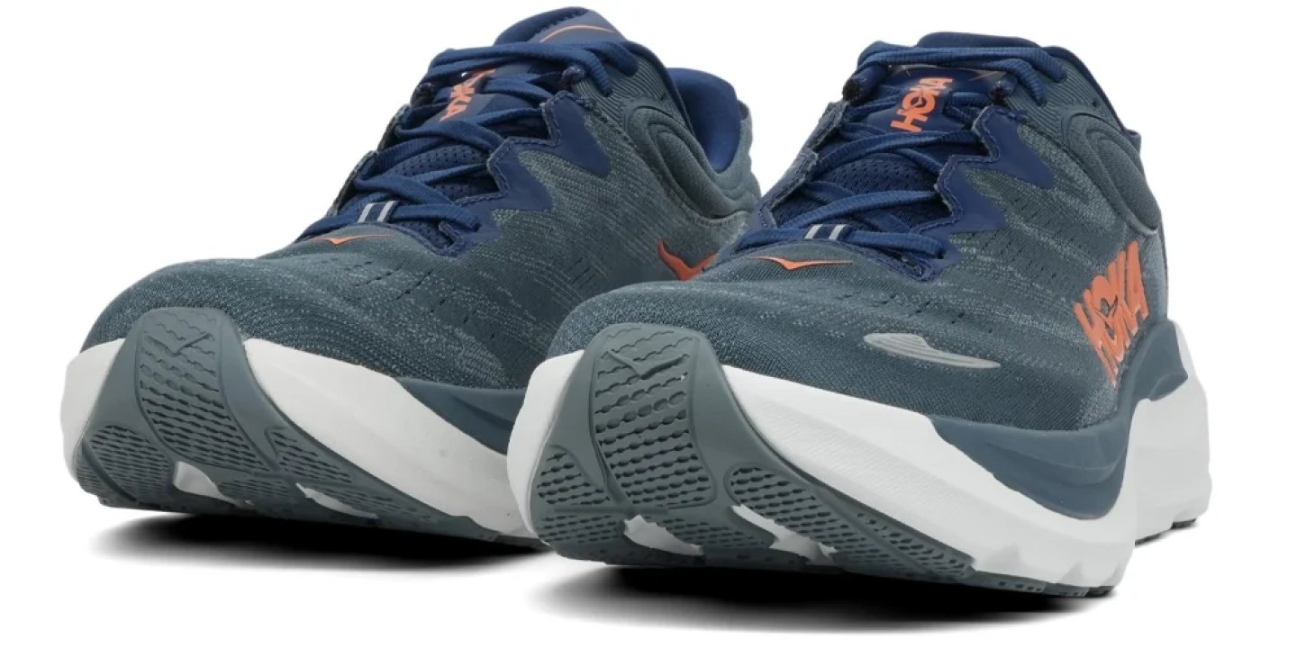 Pair of HOKA running shoes in blue-grey mesh with orange logo and thick white cushioned midsole, rear angle view.